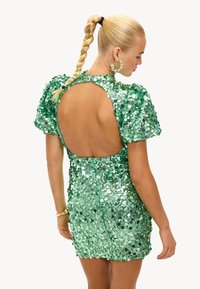 Vestido verde con lentejuelas, mangas cortas abullonadas, diseño de espalda descubierta, silueta ajustada y textura brillante.