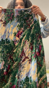 Φόρεμα με λουλουδάτο σχέδιο σε πράσινο, μπλε και κίτρινο χρώμα. Διακοσμημένο με δέντρα, σπίτια και ρέουσα σιλουέτα. Το ύφασμα φαίνεται ελαφρύ με απαλό υφή.