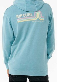 Jasnoniebieska bluza z kapturem, z przednią kieszenią, kapturem na sznurku i retro logo "RIP CURL" w pastelowych kolorach na plecach. Miękka w dotyku.