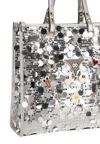 Bolso de mano plateado cubierto de grandes lentejuelas brillantes con broches caprichosos que incluyen ojos, estrella, corazón, huevo frito y pines con palabras.