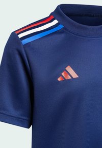 Marinblå atletisk t-shirt med röda, vita och blå randiga detaljer på axlarna och en röd broderad logotyp på bröstet.