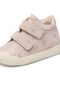Scarpa alta in suede rosa chiaro con due cinturini in velcro, dettagli dorati lucidi e un motivo di fiocchi dorati. Suola in gomma crema.