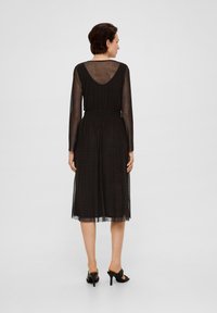 Zwarte midi-jurk met lange doorzichtige mouwen, een ruches taille en een diepe V-achterkant. Kenmerkt zich door een gelaagd, lichtgewicht stof voor een gestructureerde uitstraling.