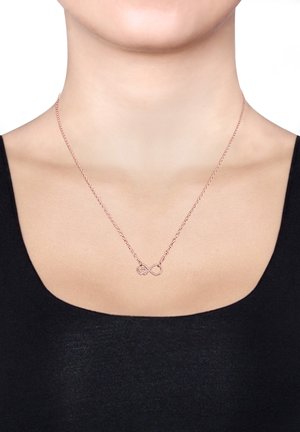 Roségoldene Halskette mit einem Unendlichkeitssymbol und Herzdesign. Die Kette ist zart und schlank und liegt auf einem nackten Hals über einem schwarzen Oberteil.