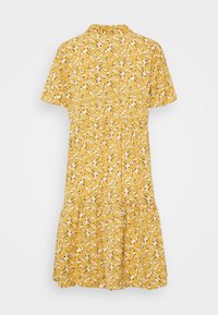 Żółta sukienka w kwiaty z kołnierzykiem, krótkimi rękawami i wielopoziomowym dołem. Posiada małe białe i zielone wzory kwiatowe na całej powierzchni.