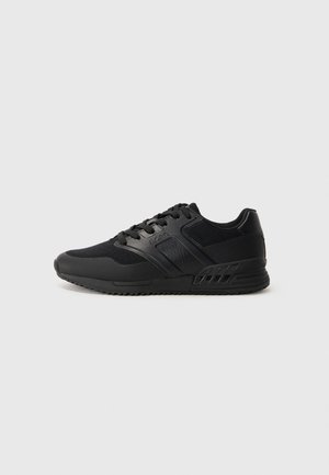 Svart lav topp sneakers med overdel i mesh og syntetisk skinn, snøring og teksturert gummisåle, sidebilde på hvit bakgrunn.