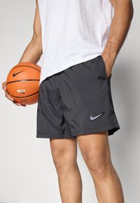 Svart Nike basketballshorts med en glatt finish, med en subtil logo i lilla, sammen med en basketball i orange farge.
