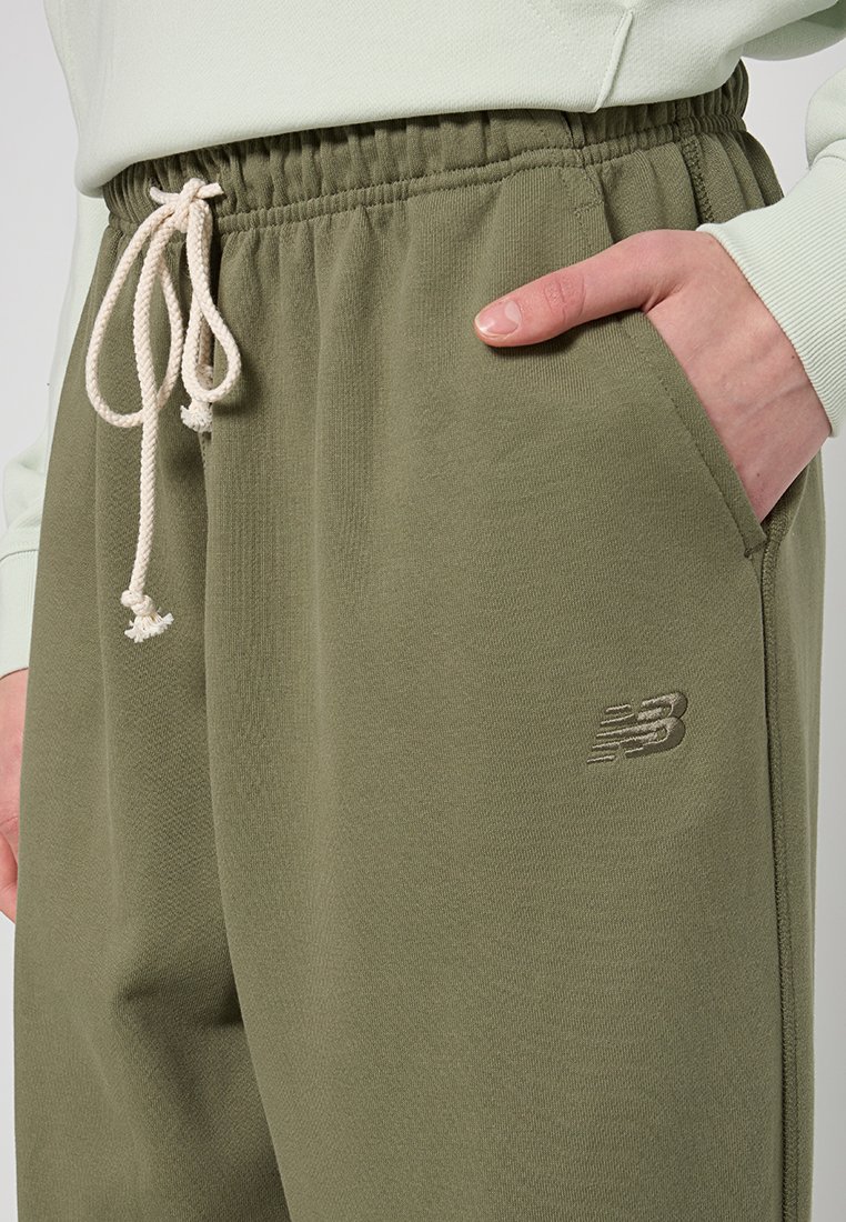 Pantalons de survêtement vert olive avec taille élastique et cordon de serrage ajustable, présentant un petit logo brodé sur la jambe gauche.