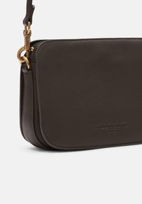 Borsa a tracolla in pelle marrone scuro con finitura texturizzata, dotata di accessori in oro e chiusura a zip. Logo del brand embosso in modo discreto sulla parte anteriore.