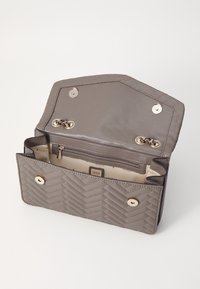 Grå quiltet syntetisk læder tegnebog med guldfarvet hardware. Har en lynlås lomme og to trykknapslukninger, som åbner op til et beigefarvet interiør med logo.