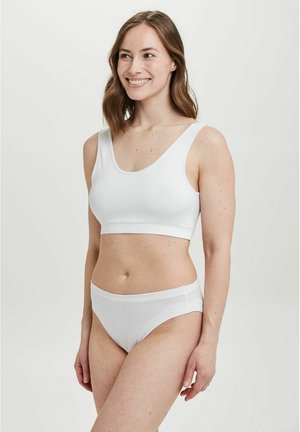 Hvid bomuldsbralette med brede stropper og scoop-udskæring, parret med matchende lavtaljede trusser, der har en glat tekstur og et minimalistisk design.