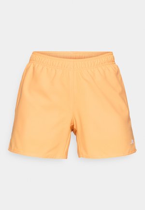 Persikka värvi spordishortsid elastse vöökohaga, sile tekstuur ja väike valge logo all paremal küljel.