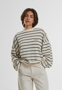 Maglione con righe orizzontali blu navy su sfondo crema. Presenta un collo a giro e una vestibilità ampia; logo ricamato "Proibito" sul petto.