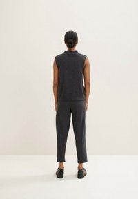 Mörkgrå ärmlös tröja och matchande smalbyxor, tillverkade av mjukt material, visade från baksidan mot en enfärgad bakgrund.