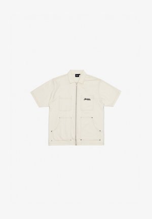 Krátky rukáv krémová bunda vyrobená z ťažkej látky so zipsovým zapínaním, dvoma prednými vreckami a vyšitým logom "HACKER" v čiernej farbe.