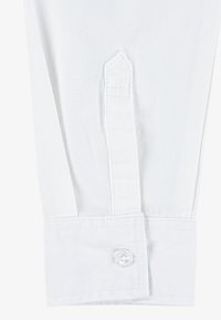 Cuff di camicia in cotone bianco con un'apertura a punta, cuciture pulite e un bottone di plastica con un motivo floreale. Texture liscia e design elegante.