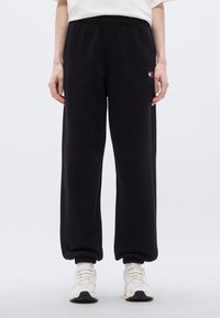 Μαύροι φόρμες από μαλακό ύφασμα, με ελαστική μέση και μανσέτες. Περιλαμβάνει μικρή λεπτομέρεια με λογότυπο στο μηρό.