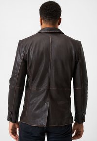 Braune Lederjacke mit glatter Textur, ausgestattet mit einem Reverskragen, Knopfärmeln und sichtbaren Nähten auf der Rückseite.