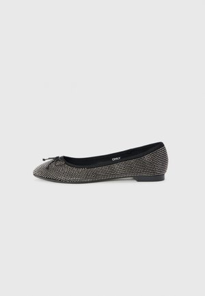 Ballerines noires avec de petites clous argentés sur toute la surface, un petit nœud sur le bout, et une semelle plate sur fond blanc.