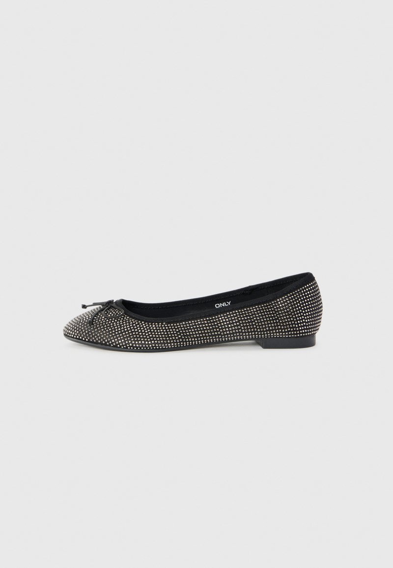 Ballerines noires avec de petites clous argentés sur toute la surface, un petit nœud sur le bout, et une semelle plate sur fond blanc.