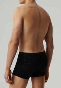 Czarne bokserki w małe, wielokolorowe kropki, z miękkim pasem. Materiał wydaje się gładki i ma dopasowany krój.