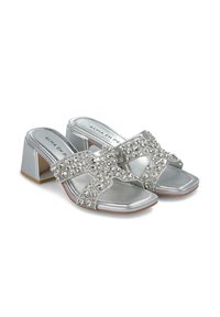 Sandali con tacco quadrato in argento con una finitura lucida, dotati di cinturini incrociati decorati con strass trasparenti. Design con punta quadrata e soletta imbottita.