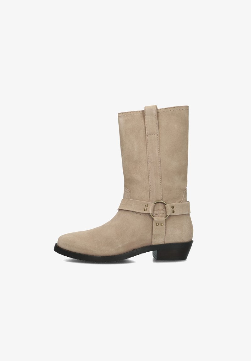 Beige suède enkellaars met een taps toelopende neus, platte hak en zijband met een ronde metalen accent. Gladde textuur, minimale stiksels.