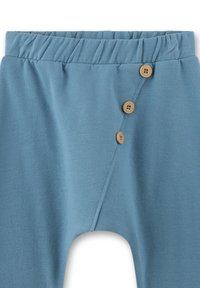 Blaue Baumwollhosen mit elastischem Bund, ausgestattet mit einem diagonalen Knopfverschluss mit Holzknöpfen und einer glatten Textur.