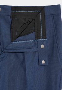 Granatowe spodnie eleganckie z zamkiem błyskawicznym, czarnym paskiem w talii, wzmocnionymi szwami i srebrnymi elementami metalowymi przy zapięciu.