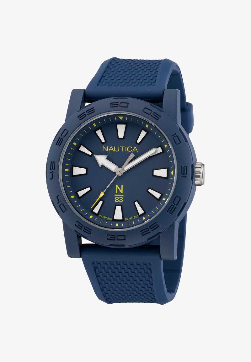 Sinine kummirihmaga kell sinise sihiku, valgete tunni markerite ja kollaste aktsentidega. Omab ümmargust korpust ja sisaldab kroonit, et teha seadistusi.