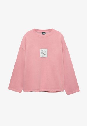 Felpa rosa a maniche lunghe con vestibilità rilassata, caratterizzata da una toppa quadrata con testo scritto a mano sul petto e una morbida texture in cotone.
