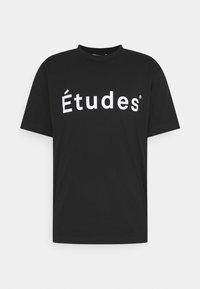 T-shirt noir à manches courtes et col rond avec le texte "Études" en blanc centré à l'avant.