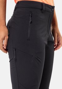 Black trousers with a fitted design, featuring zippered side pockets, stretch fabric, and subtle stitching details for enhanced durability.
