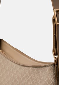 Borsa beige con un design testurizzato che presenta un motivo geometrico. Materiale liscio, base piatta e tracolla regolabile con dettagli in metallo dorato.