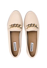 Beige Leder Slipper mit einer goldenen und schwarzen Kettenakzent entlang der Vorderseite. Flache Sohle und gepolsterte Innensohle für Komfort. Offenes Zehendesign.