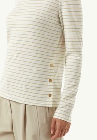 Rippstrick Langarmshirt in Creme mit feinen goldenen Streifen. Verfügt über drei goldene Knöpfe an der Seite und hat eine figurbetonte Passform.