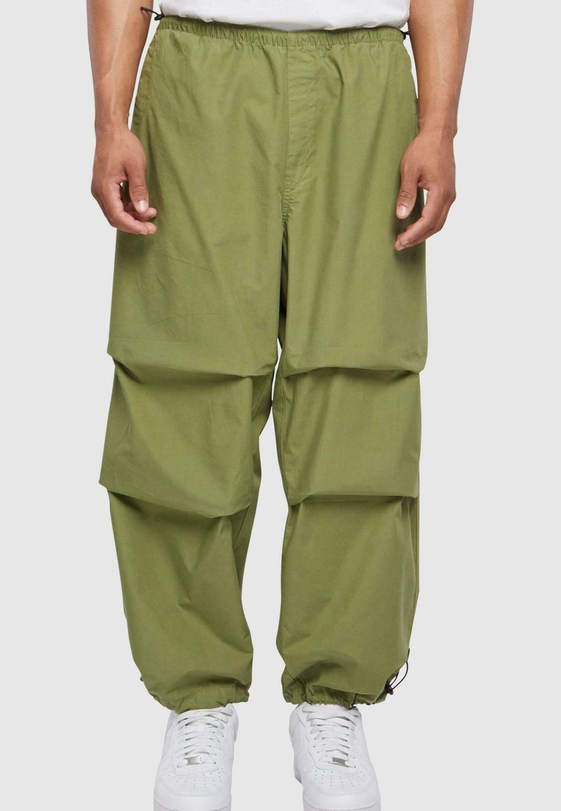 Grønne cargo-bukser med elastisk liv, med flere store lommer og rynkede mansjetter. Brukt med hvite sneakers.