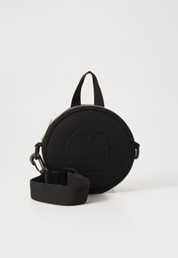Black round bag made of fabric with a zipper closure, featuring a prominent embossed logo, a top handle, and a detachable strap.