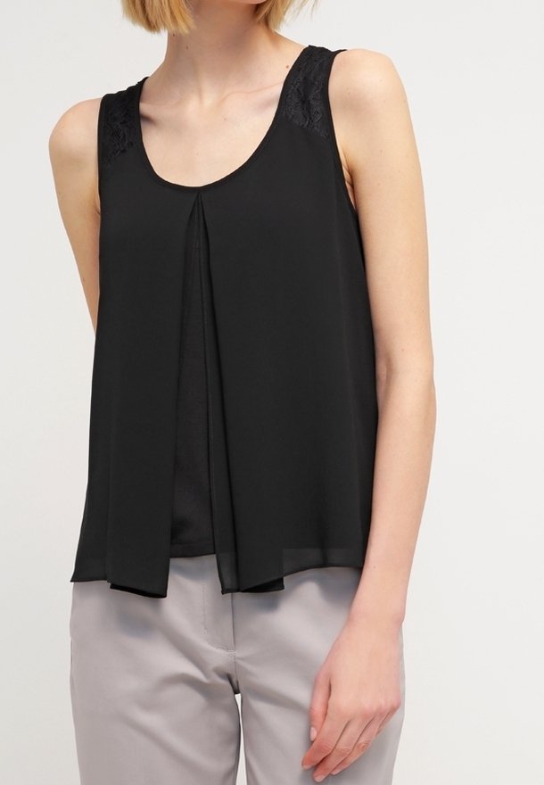 Černý top bez rukávů s krajkovými detaily na ramenou, lehký materiál, splývavý design a přední sklady, spojený se světle šedými kalhotami.