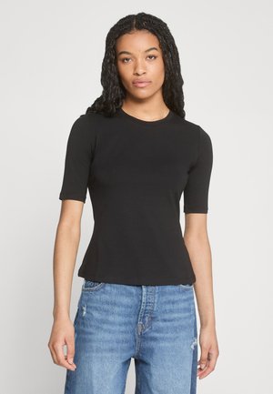 Schwarzes, tailliertes T-Shirt mit kurzen Ärmeln, runder Ausschnitt und glatter Struktur. Kombiniert mit ausgewaschenen blauen Jeans.