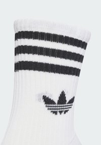 Weißer Crew-Socke mit schwarzen Streifen oben und einem schwarzen Adidas-Trefoil-Logo. Hergestellt aus strukturiertem Strickmaterial.