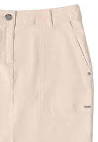 Světle béžové kalhoty vyrobené z měkké tkaniny, které mají přední kapsu, pevný kovový knoflík a prošívané detaily. Logo se nachází na bočním švu.