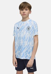 Zils un balts svītrots īsās piedurknes futbols krekls ar apaļu kakla izgriezumu un logo krūtīs. Nēsāts ar tumšām biksēm, kurām ir balts logo.