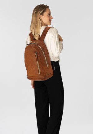 Zaino in pelle marrone con texture liscia, scomparti con zip e spallacci regolabili. Caratteristiche includono un fondo arrotondato e un design elegante.