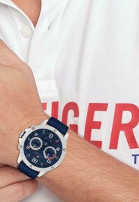 Reloj azul marino con acentos plateados y un dial texturizado. Cuenta con múltiples sub-diales de cronógrafo y una correa de silicona azul.