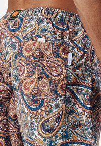 Bañadores de paisley coloridos, hechos de un tejido ligero, con cinturilla elástica y un bolsillo lateral con botón.