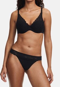 Black lace bra and matching thong featuring scalloped edges, delicate floral pattern, and thin adjustable straps. Smooth fabric finish.