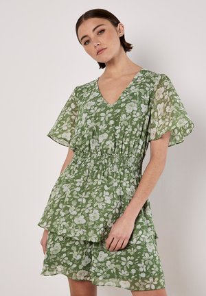 Groene bloemenjurk met een v-hals, korte fladdermouwen en een gesmokt middel. Lichtgewicht, gelaagd ontwerp met een doorschijnende textuur en zachte stof.