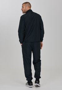 Svart träningsjacka och byxor i set, med ståkrage, elastiska manschetter och tapered ben-design. Texturerad tyg med en mjuk finish.