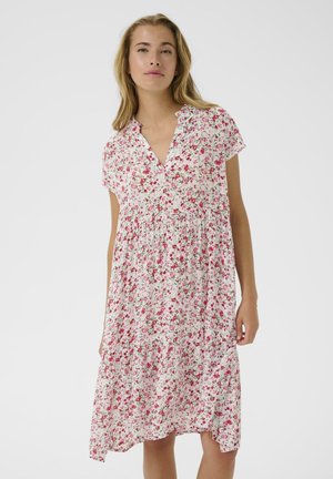 Kwiatowa sukienka na białym tle, z krótkimi rękawami, dekoltem w kształcie litery V, zgromadzonym w talii oraz różowo-zielonymi wzorami kwiatowymi na całej powierzchni.